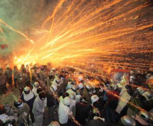 --FILE--Visitors wearing helmets get sprayed by fire sparks from exploding bottle rockets during the Yanshui Beehive Rockets Festival in Yanshui Distr